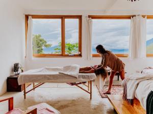 Una mujer está haciendo una cama en un dormitorio en Designers Luxury Retreat with breathtaking gardens, en Tzununá