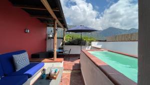 a swimming pool with a blue couch and an umbrella at Hotel El Ciruelo, Tepoztlán in Tepoztlán