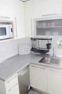 a white kitchen with a sink and a microwave at La morada del viajero in Granada