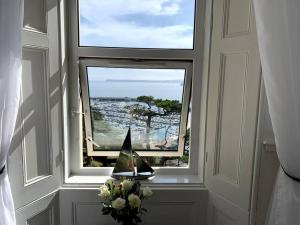 a window with a sail boat in a vase of flowers at Waterside & Marina View Apartment in Torquay in Torquay