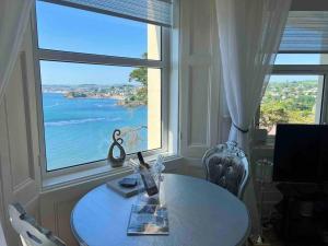 a table in front of a window with a view of the ocean at Waterside & Marina View Apartment in Torquay in Torquay