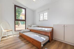 2 camas en una habitación con ventana y silla en CARCAVELOS CHALLET en Carcavelos
