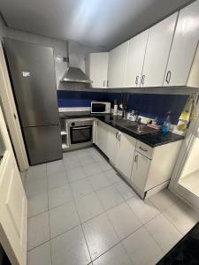 a kitchen with white cabinets and a stainless steel refrigerator at Torremolinos habitaciones privada en apartamentos compartidos in Torremolinos
