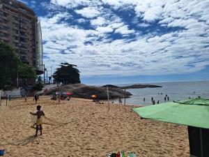 eine Person, die am Strand mit einem Drachen steht in der Unterkunft Apartamento a 4 min a pé da Praia das Castanheiras in Guarapari