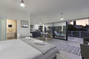 a bedroom with a large white bed and a kitchen at Korhaan House in Melkbosstrand