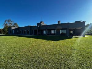 a large building with a grass field in front of it at Casa de campo en Capilla del Señor in Capilla del Señor