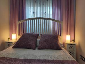 uma cama com duas almofadas num quarto com cortinas cor-de-rosa em Ático - Piscina Málaga centro em Málaga