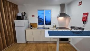 a kitchen with a white refrigerator and a sink at A m a r - 450m from the beach in São Roque