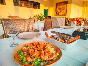 uma mesa com um prato de camarão e uma salada em Planet Dunas Residence em Aquiraz