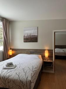 Auberge Morritt في مونت تريمبلانت: غرفة نوم بسرير ومصباحين ومرآة