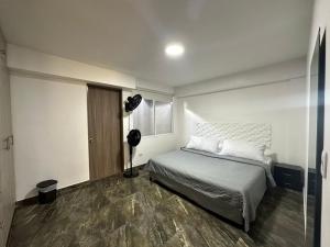 a bedroom with a bed and a fan in it at Olmo Apartahotel in Pereira