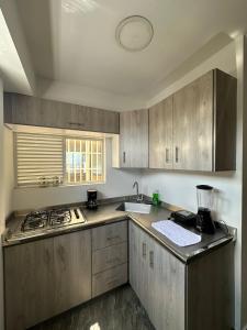 uma cozinha com armários de madeira e um forno com placa de fogão em Olmo Apartahotel em Pereira