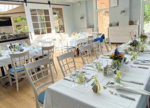 een restaurant met witte tafels en stoelen met bloemen erop bij Ferienhaus Tina in Wirdum