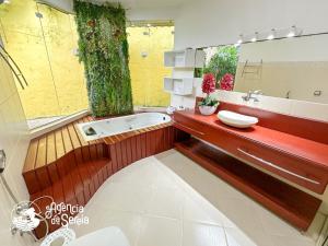 伊利亞貝拉的住宿－Casa incrível em Ilhabela com piscina e vista mar，带浴缸、水槽和镜子的浴室
