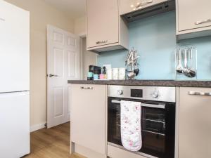 a kitchen with white cabinets and a black oven at Tremethic in St Austell