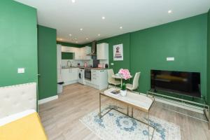 een woonkamer met groene muren en een tafel met bloemen bij Free Parking Guaranteed Weekly & Monthly Stay Savings Close to City Centre in Reading