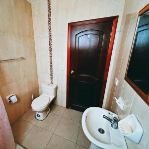 La salle de bains est pourvue de toilettes, d'un lavabo et d'une porte noire. dans l'établissement Departamento Vacacional en el Centro de Loja, à Loja