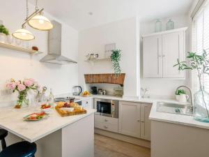 una cocina con armarios blancos y una mesa con un bol de fruta en 1 Bed in Saltaire 83634 en Shipley