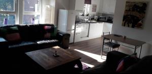 a living room with a couch and a table and a kitchen at Spacious Modern Apartment in Glasgow