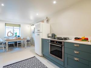 a kitchen with blue cabinets and a white refrigerator at 2 Bed in Stratford upon Avon 77617 in Wellesbourne Hastings