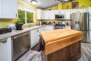 uma cozinha com armários brancos e um balcão de madeira em The Nest-2 K Beds-Game Room-Deck-5 min to Mariposa em Mariposa