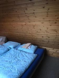 a bed in a room with a wooden wall at Haus Imgard in Lenzkirch