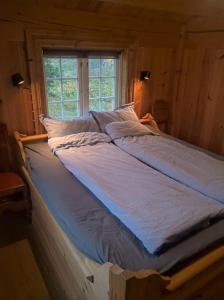 Solehøgda 71. Unik tømmerhytte som er håndlaget في Surteberg: سرير كبير في غرفة مع نافذة