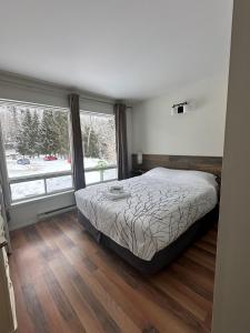 a bedroom with a bed and a large window at Auberge Morritt in Mont-Tremblant