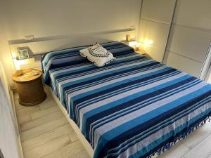 Una cama con una manta de rayas azul y blanca. en Isola di Marettimo casa vacanze en Marettimo
