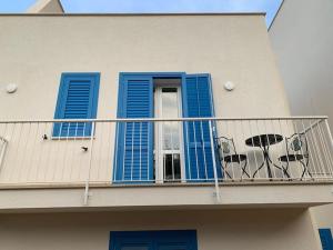 un balcón con persianas azules y una mesa. en Isola di Marettimo casa vacanze en Marettimo