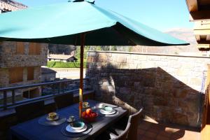 una mesa bajo una sombrilla en un balcón en Can Vilà- Vall de Camprodon, en Vilallonga de Ter