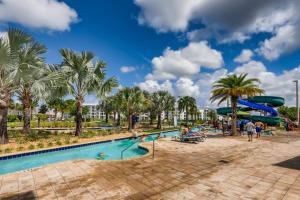 een zwembad in een resort met palmbomen en een glijbaan bij Storey Lake Resort Near Disney Universal in Kissimmee