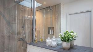 a bathroom with a shower with plates and flowers on a counter at The Garden Room - 1 bedroom annex in Penrith in Penrith +12 photos