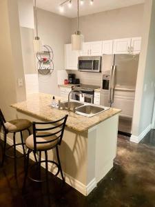 cocina con fregadero y encimera con 2 sillas en Luxe Lavish w/ Pool en Houston