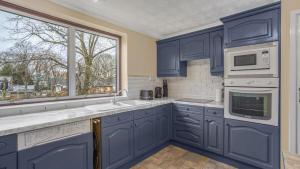 a kitchen with blue cabinets and a window at Park Avenue - An Executive 2 Bed Suite Close to Birmingham City Centre in Birmingham