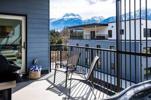 a chair on a balcony with a view of mountains at Mountain Revelation - Stunning Condo in Revelstoke in Revelstoke