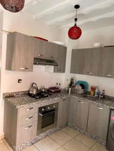 uma cozinha com armários de prata e um fogão forno superior em Appartement 5 piscines fitness em Marrakech
