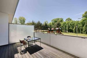 a table and chair on a balcony with a view of a playground at Komfortowy apartament z siłownią i sauną Revisit Apartment 11 in Łódź