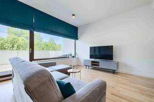 a living room with a couch and a flat screen tv at Komfortowy apartament z siłownią i sauną Revisit Apartment 11 in Łódź