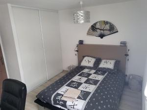 1 dormitorio con 1 cama y 1 silla negra en Gîte chez Laurence, en Les Fins