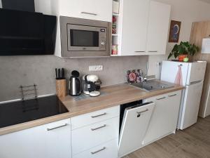 cocina con armarios blancos, fregadero y microondas en Apartmány Svítkov 79, en Pardubice