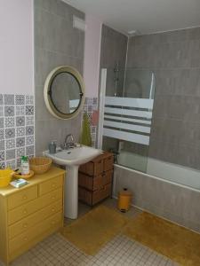 a bathroom with a sink and a mirror and a tub at Charmante Maison à Coutances in Coutances