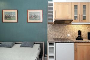 Una pequeña habitación con una cama y una cocina. en Élégant appartement aux portes de paris, en Saint-Ouen