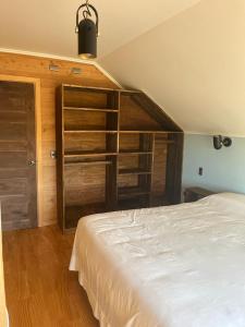 プエルト・オクタイにあるRefugio Serenoの白いベッドと木製の棚が備わるベッドルーム1室