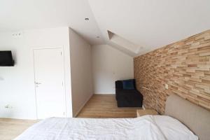 Un dormitorio con una pared de ladrillo y una cama en Recreatiedomein Warredal - The Lodge, en Neeroeteren