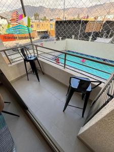 uma varanda com 2 cadeiras e uma piscina em NUEVO E IMPECABLE A PASOS DEL MAR em Antofagasta