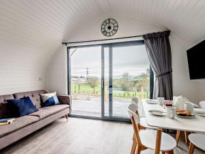 un soggiorno con divano, tavolo e orologio. di 2 Bed in Corwen 80318 a Gwyddelwern