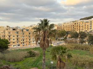 una palmera frente a un gran edificio en Paradise 1 en Żebbuġ