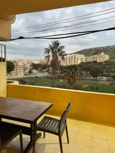 una mesa y una silla en un balcón con vistas a la ciudad en Paradise 1 en Żebbuġ