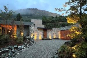 una casa de piedra con una pared de piedra y un camino de entrada en 45 Degrees South BBQ Hot TubPrivate, en Queenstown